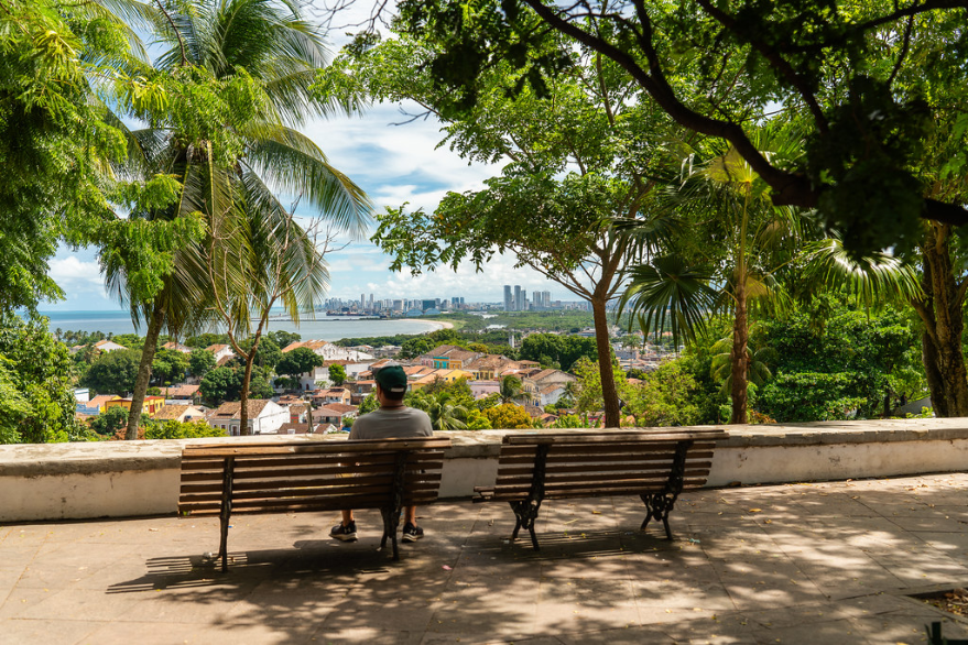 Traveler sitting on a bench overlooking a Brazilian coastal city